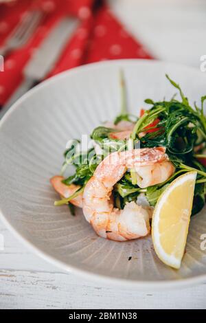 Frischer Salat mit Garnelen, Rucola, Zitrone, Tomaten aus Bio-Produkten. Draufsicht. Stockfoto
