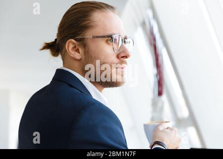 Bild von attraktiven konzentriert jungen Geschäftsmann drinnen im Büro beiseite schauen. Stockfoto