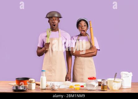 Schockiert afroamerikanischen Paar in Mehl Backen zusammen auf farbigen Hintergrund bedeckt Stockfoto