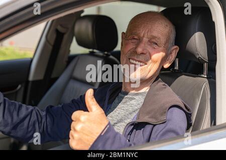 Ältere glücklich Casual Mann fahren das Auto und zeigt den Daumen Stockfoto