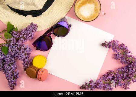 Unbeschriftete Notizblätter, umgeben von lila Farben, Sonnenbrillen, bunten Makronen und einem Strandhut. Stilvolles minimalistisches Arbeitsplatzkonzept. Draufsicht mit Stockfoto