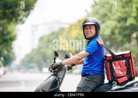Portrait von fröhlichen vietnamesischen Mann mit großen Kühltasche Arbeit für Lieferservice Stockfoto