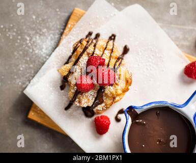 Süße Waffeln auf einem Tisch mit frischen Himbeeren und Schokolade dekoriert. Stockfoto