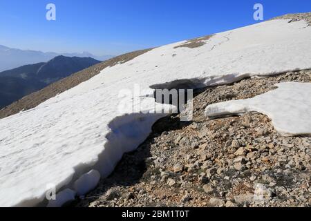 Landschaft mit geschmolzenem Schnee auf Berghang unter blauem Himmel Stockfoto