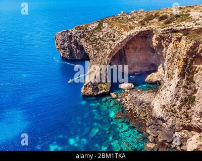 Blaue Grotte in Malta. Ausflugsboot mit Touristen läuft. Natürliches Bogenfenster im Fels. Luftaufnahme von oben Stockfoto