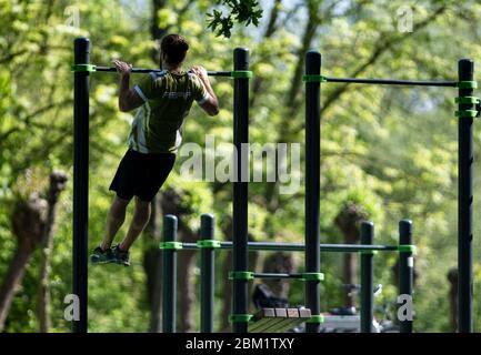 Hannover, Deutschland. Mai 2020. Mit Pull-Ups hält ein Freizeitsportler fit auf einem Outdoor-Fitness-Platz. Ab diesem Mittwoch werden in Niedersachsen weitere Beschränkungen gelockert, die im Zuge der Corona-Pandemie verhängt wurden. Diese betreffen vor allem Freizeitaktivitäten. Sport auf Outdoor-Anlagen ist wieder möglich, aber all dies unter strengen Hygiene- und Entfernungsanforderungen. Quelle: Peter Steffen/dpa/Alamy Live News Stockfoto