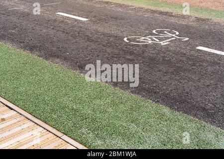 Fahrradweg mit einem Symbol für ein Fahrrad, neben einer Fußgängerzone aus Holz. Sport und Erholung, aktiver Lebensstil. Stockfoto