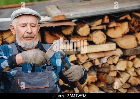 Senior Smiling man schärft Werkzeug für die Kultivierung von Bauernboden. Landwirtschaftskonzept Stockfoto