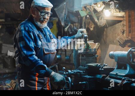 Ältere ältere männliche Dreher bearbeiten Metall an der Maschine. Konzept Rentenarbeiter Industrie, Arbeitsplatz Stockfoto