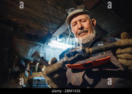 Ältere ältere männliche Dreher bearbeiten Metall an der Maschine. Konzept Rentenarbeiter Industrie, Arbeitsplatz Stockfoto