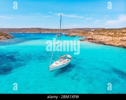 Weiße Yacht steht in azurblauem transparentem Wasser Meer, Strand Blue Lagoon Comino Malta. Luftaufnahme Stockfoto