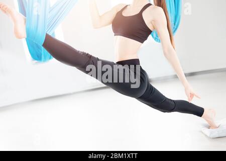 Junge Frau, die in einem weißen Studio Yoga mit Antigravitation durchführt Stockfoto