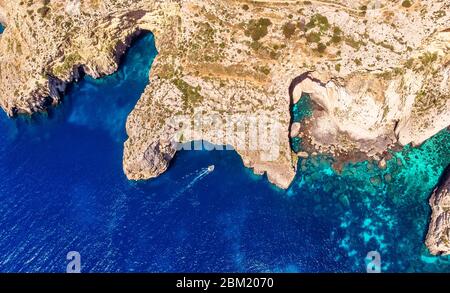 Blaue Grotte in Malta. Ausflugsboot mit Touristen läuft. Natürliches Bogenfenster im Fels. Luftaufnahme von oben. Stockfoto