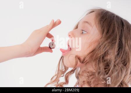 Fröhliches Mädchen spielt und isst Schokolade rund Süßigkeiten auf einem leichten Hintergrund, Welt Schokolade day.Children und Schokolade. Stockfoto