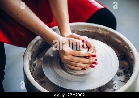 Hände der Frau machen Tongeschirr auf dem Töpferrad, Draufsicht. Eleganz des Konzepts Stockfoto