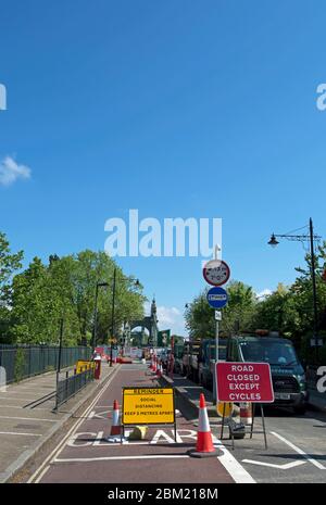 Schilder, die auf soziale Distanz hindeuten und die Straße geschlossen sind, außer für Fahrräder auf der südlichen Zufahrt zur hammersmith-Brücke, london, england Stockfoto