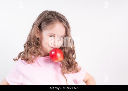 Kinder und Schokolade. Ein fröhliches Mädchen wählt zwischen Schokolade und Äpfeln. Gesunde Ernährung Stockfoto