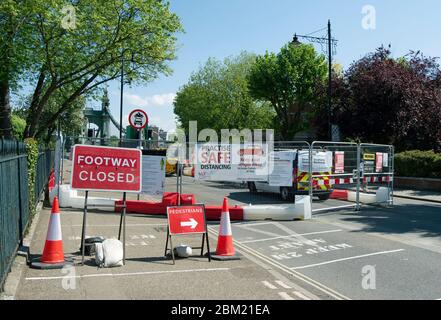 Schilder und Banner zeigen sichere Entfernung, eine geschlossene Fußwege und Fußgängerweg an der südlichen Zufahrt zur hammersmith Bridge, london, england Stockfoto