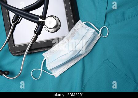 Stethoskop, chirurgische Maske und medizinische Tablet-Computer auf einem Satz von chirurgischen Grüns, Scrubs. Stockfoto