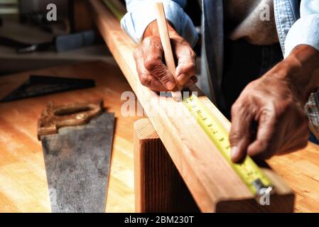 Nahaufnahme eines Holzarbeiters in seiner Werkstatt, der ein Brett zum Schneiden markiert. Stockfoto