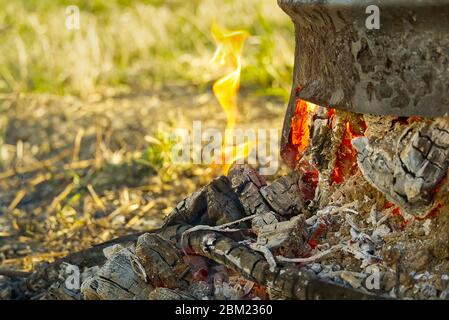 Kohlen in einem Metallfass auf dem Hinterhof. Schwelbrand in einem runden Metallfass nach dem Verbrennen trockener Äste. Stockfoto