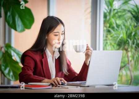 Porträt der jungen asiatischen Geschäftsfrau sitzt drinnen im Café trinken Kaffee mit Laptop-Computer. Business Success Concept. Stockfoto