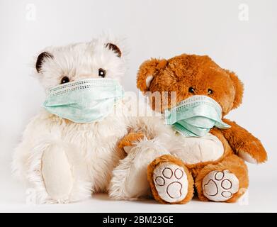 Freundschafts- und Betreuungskonzept. Zwei Bären sitzen in schützenden medizinischen Masken auf weißem Hintergrund. Stockfoto