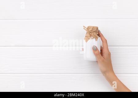 Frauen Hand hält Flasche Milch oder yougurt auf weißem Holzhintergrund Stockfoto