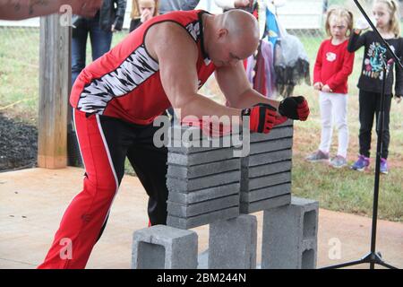 Starker Mann, der bereit ist, einen Haufen Steine mit seinen Händen während einer Live-Performance zu brechen Stockfoto