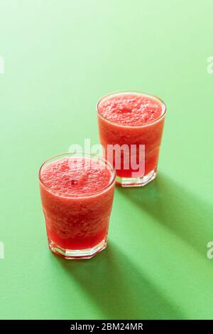 Süße Wassermelone auf grünem Hintergrund in rauem Licht. Zwei Gläser Wassermelone Eisgetränk. Sommermocktail. Erfrischendes Getränk. Stockfoto