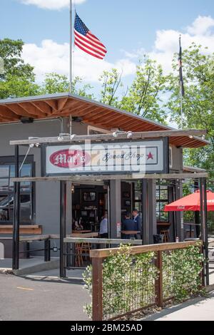 Charlotte, NC/USA - 14. Mai 2019: Vertikale Mittelaufnahme der Bar und des Grills 'Mac's Speed Shop' mit Marken- und Logo-Schildern und amerikanischer Flagge auf dem Dach. Stockfoto