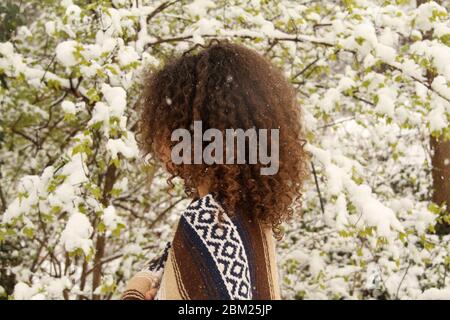 Ein junges Mädchen draußen im Hof während des Schneesturms Stockfoto