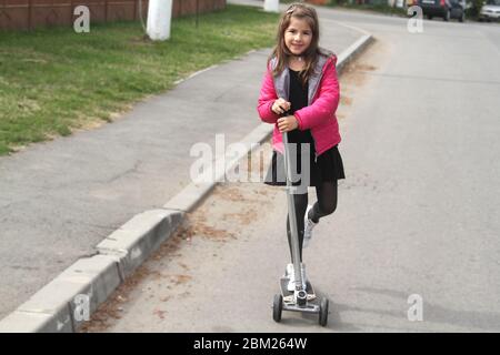 Kleines Mädchen auf dem Roller auf der Straße Stockfoto