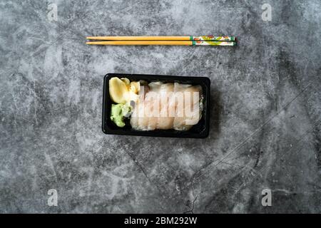 Zum Mitnehmen Suzuki Fisch Sashimi mit eingelegtem Ingwer und Wasabi in schwarzem Kunststoff-Teller-Container / Paket. Traditionelles Fast Food. Bereit zum Essen. Stockfoto