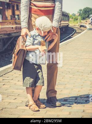 Ängstlicher Junge in 1940er-Kostüm auf Plattform der britischen Erbe Dampfeisenbahn mit Vater, WW2 Kriegszeit Großbritannien Sommerereignis gekleidet. Stockfoto