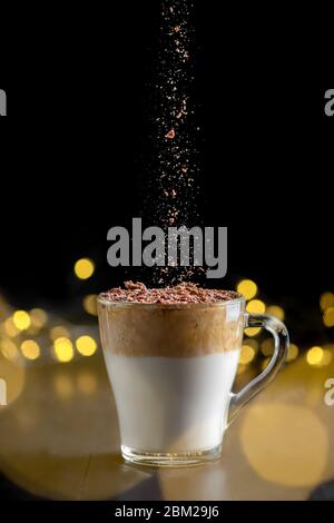 Dalgona Kaffee auf schwarzem Hintergrund mit Lichtern und Schokoladenpulver gegossen Stockfoto