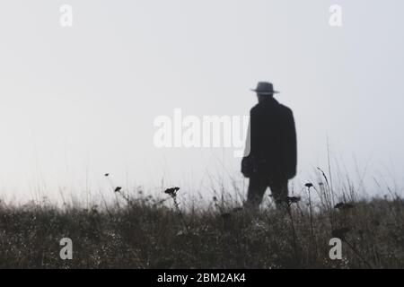 Ein Mann, der einen Fedora-Hut trägt, der an einem nebligen Wintertag aus dem Fokus herausragt Stockfoto