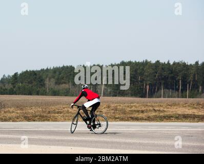 Fröhliche männliche Radfahrer Radfahren in leeren Straße während der Coronavirus (COVID-19) Pandemie Sperrung, überqueren die Straße, genießen die Aussicht, kopieren Raum. Ath Stockfoto