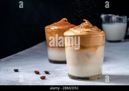 Iced Dalgona Kaffee auf dunklem Hintergrund. Trendy Cremigen Schlagsahne Kaffee. Südkoreanischer Kaltsommer-Drink Stockfoto