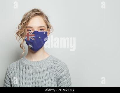 Junge Frau mit einer Schutzmaske mit Nationalflagge australien. Konzept für Grippeepidemie und Virenschutz Stockfoto