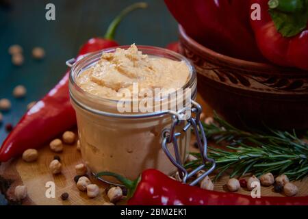 Hausgemachter Hummus mit rotem Pfeffer auf einem Holztisch. Selektiver Fokus und geringe Schärfentiefe Stockfoto