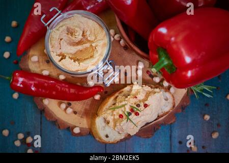 Hausgemachter Hummus mit rotem Pfeffer auf einem Holztisch. Selektiver Fokus und geringe Schärfentiefe Stockfoto