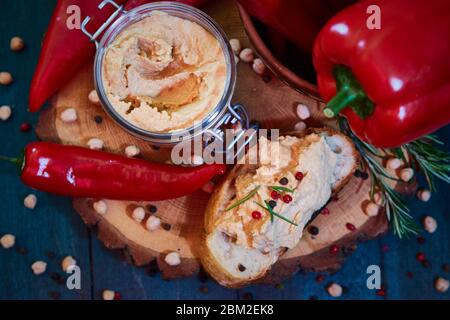 Hausgemachter Hummus mit rotem Pfeffer auf einem Holztisch. Selektiver Fokus und geringe Schärfentiefe Stockfoto