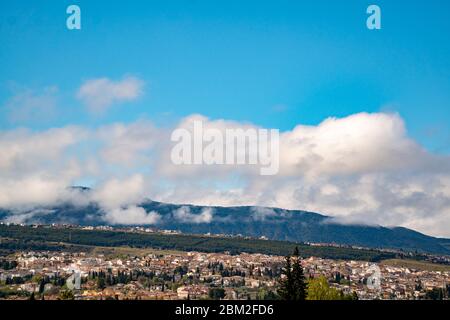 Niedrige schwebende Wolken über einem Dorf in den Bergen. Panoramablick auf tief hängende weiße Wolken in den Bergen. Stockfoto
