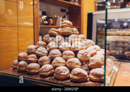 Haufen Donuts auf Café-Vitrine. Stapel von Desserts mit Zuckerpulver auf Regal im Geschäft. Stockfoto