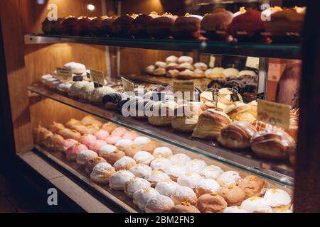 Auswahl an Donuts auf Café-Vitrine. Verschiedene Desserts mit verschiedenen Geschmacksrichtungen auf Regalen im Geschäft. Stockfoto