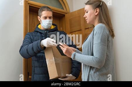 Männliche Kurier in medizinischen Maske und Handschuhe liefert Paket. Stockfoto