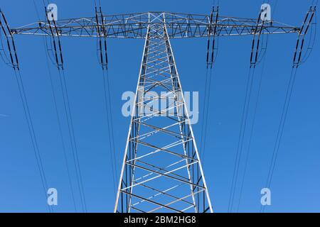 Strommast in der Mitte von unten unter blauem Himmel Stockfoto