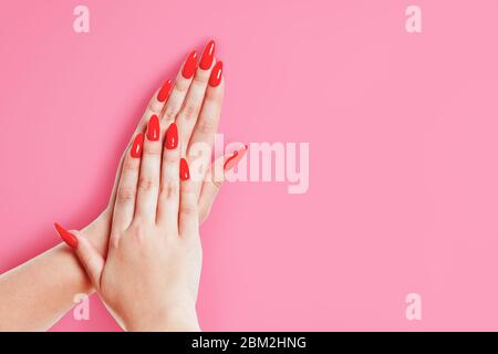 Stilvolle modische weibliche rote Maniküre, auf einem rosa Hintergrund. Stockfoto