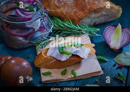 Hering, rote Zwiebel und Roggenbrotscheibe auf einem alten Holztisch Stockfoto